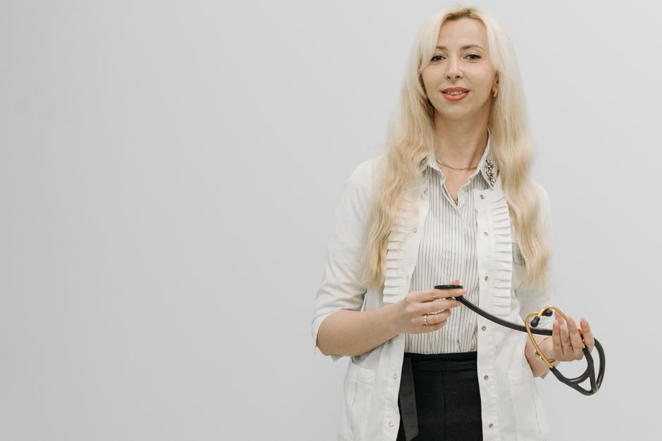 Blonde female doctor with a stethoscope against a white background, representing healthcare professionals.